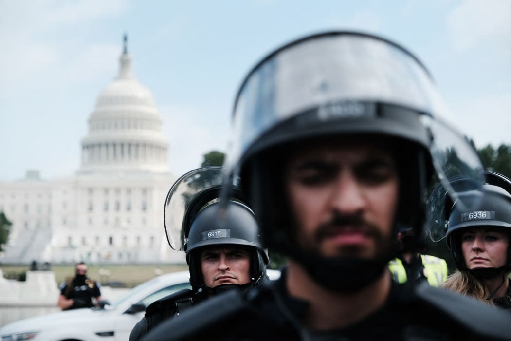 Police in riot gear stand in front of the US Capitol during the Justice for J6 rally.