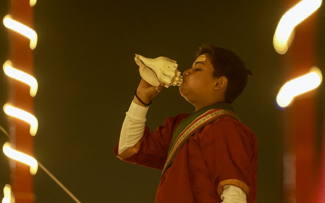 A student from a Hindu religious school blows a traditional conch as part of the evening prayers ahead of the Maha Kumbh Mela festival in Prayagraj on January 10, 2025. (Photo by Niharika KULKARNI / AFP)
