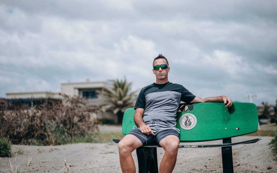Mark Inman sit on a wakeboard bench in memory of his brother tour guide Hayden Marshall-Inman whose body has not been recovered since the Whakaari White Island eruption.