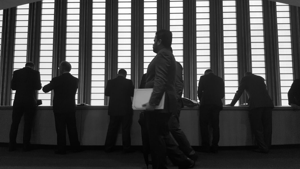 A silhouette of men in suits against a window at the United Nations in New York