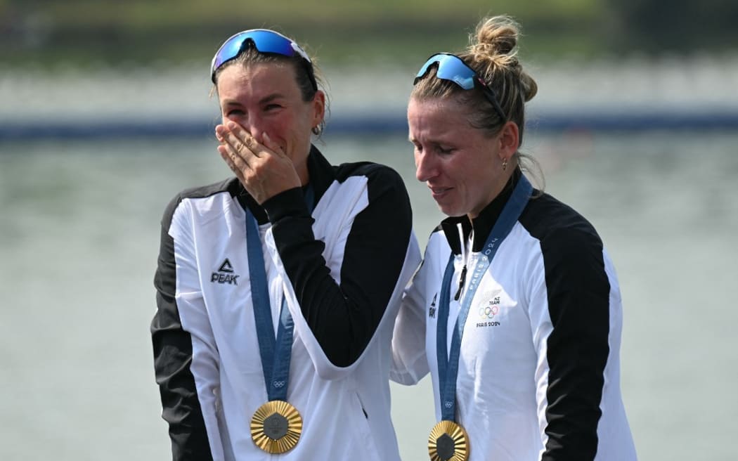 New Zealand's gold medallists Brooke Francis (R) and Lucy Spoors react as they celebrate on the podium during the medal ceremony after the women's double sculls final rowing competition at Vaires-sur-Marne Nautical Centre in Vaires-sur-Marne during the Paris 2024 Olympic Games on August 1, 2024. (Photo by Bertrand GUAY / AFP)