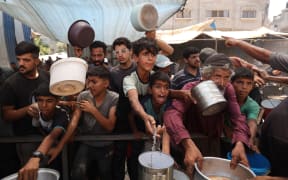 Palestinian children queue for a portion of hot food distributed by a charity kitchen at the Nuseirat refugee camp in the central Gaza Strip on July 15.