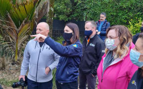 The Prime Minister Jacinda Ardern standing on silt and mud, talking to a Nelson resident after heavy rain caused extensive flooding and landslides in the area. Ms Ardern is accompanied by emergency management Minister Kieran McAnulty, the local MP Rachel Boyack and  other officials
