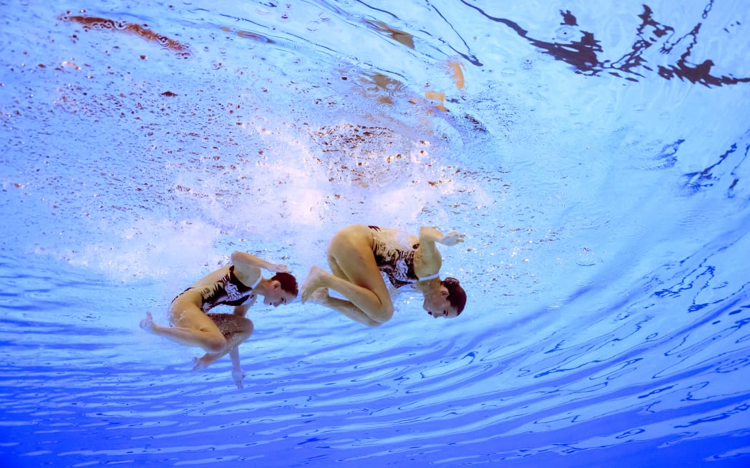 An underwater view shows New Zealand's Eva Morris and New Zealand's Nina Brown competing in the duet technical routine of the artistic swimming event during the Paris 2024 Olympic Games at the Aquatics Centre in Saint-Denis, north of Paris, on August 9, 2024. (Photo by Oli SCARFF / AFP)