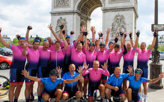 A group of riders of the 2021 Tour 21 raise their hands in the air in front of the Champs-Élysées after completing the Tour de France.