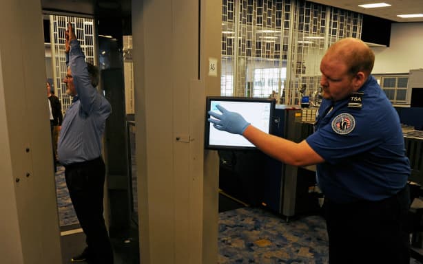 LAS VEGAS, NV - FEBRUARY 01: U.S. Transportation Security Administration supervisor Nick Fox (R) and another TSA employee demonstrate an advanced image technology (AIT) millimeter wave scanner using new Automated Target Recognition software being tested by the TSA at McCarran International Airport February 1, 2011 in Las Vegas, Nevada. The new software detects potential threat items and displays them on the outline of a generic body displayed on a monitor attached to the unit instead of using passenger-specific images. TSA officers will no longer need to use a remotely located room to view the images, which will make the process more efficient according to a TSA spokesman.   Ethan Miller/Getty Images/AFP (Photo by Ethan Miller / GETTY IMAGES NORTH AMERICA / Getty Images via AFP)