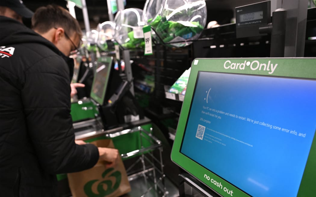 A customer takes care of his shopping next to blue screen at self-checkout terminals of a supermarket in Sydney on July 19, 2024.