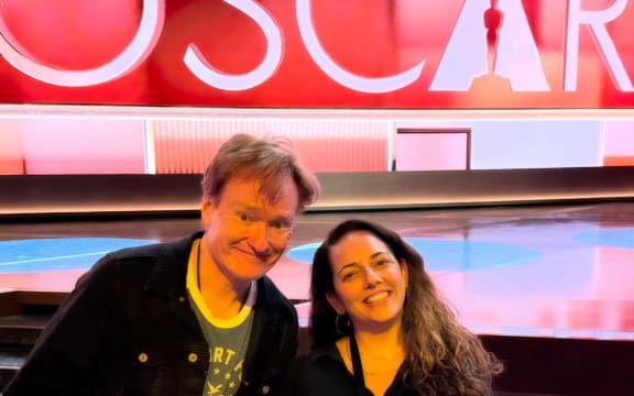 Sona Movsesian and Conan O'Brien pose in front of an illuminated sign that reads 'Oscar'.