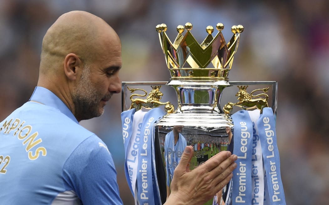 Manchester City's Spanish manager Pep Guardiola caresses the Premier League trophy as he prepares to celebrate their title 2022.
