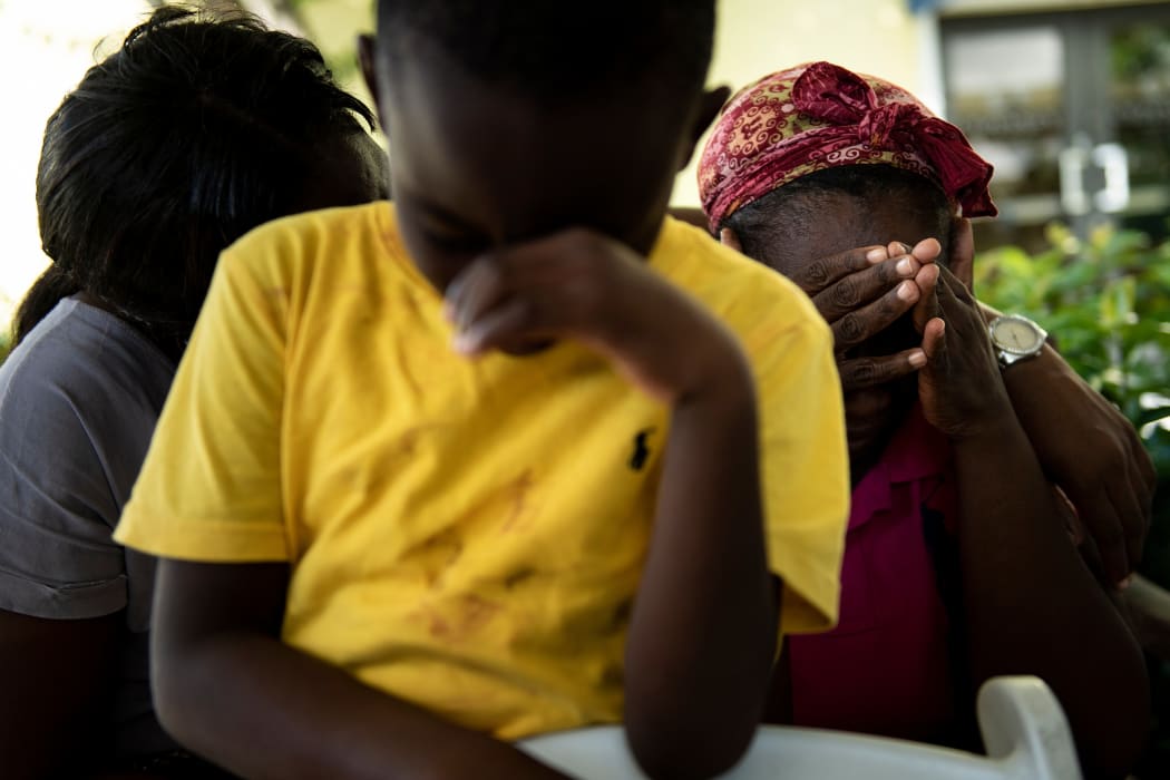 Chrishon Dowkins (C) and his grandmother Catherine Russel (R) rest after arriving with other survivors of Hurricane Dorian from Abaco island at Odyssey Aviation at Lynden Pindling International Airport September 4, 2019, in Nassau, New Providence