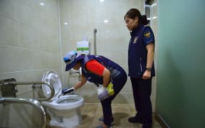 A member of Seoul city's "hidden camera-hunting" squad and a policewoman inspect a women's bathroom stall to find a "secret camera" at a museum in Seoul.