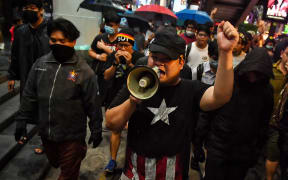 Pro-democracy activist Parit Chiwarak (centre) uses a loudspeaker as he walks with others towards the police headquarters in Bangkok on October 13, 2020.