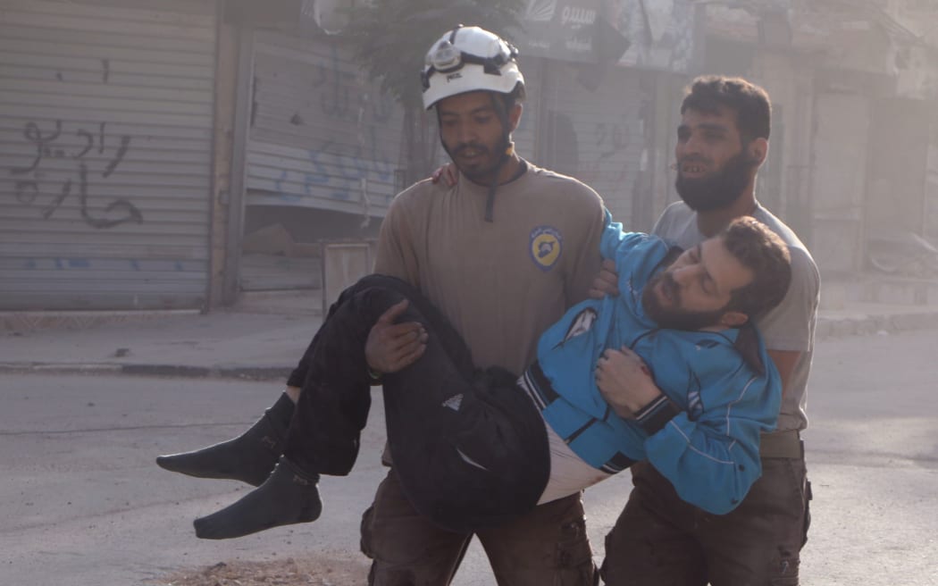 Residents of Aleppo carry an injured man after air strikes on the city.