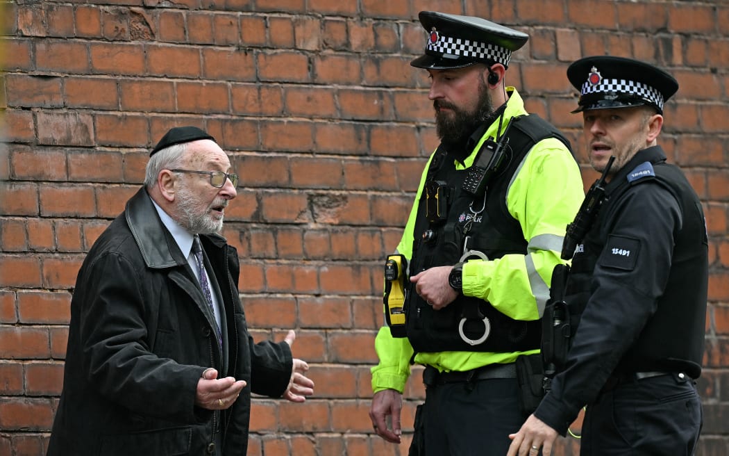 Police officers talk with a member of the local community near Heaton Park Hebrew Congregation synagogue in Crumpsall, north Manchester, on October 2, 2025, following an attack at the synagogue. Two people were killed and three wounded in a car ramming and stabbing incident outside a synagogue in Manchester, northwest England, on Thursday, police said. "A man believed to be the offender was shot by GMP (Greater Manchester Police) Firearms Officers and is also believed to be deceased," the force said on X, adding his death could not yet be confirmed due to "suspicious items on his person". (Photo by Oli SCARFF / AFP)