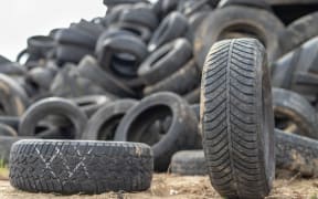 A stack of tires on an old garbage dump. Old worn out tires piled up. Season of the autumn.