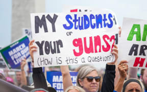 Demonstrators hold placards in a March for Our Lives 2022 rally in Washington DC calling for stricter gun laws.