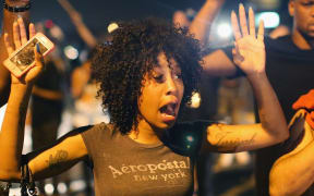 Demonstrators protesting over the killing try to stand their ground despite being overcome by tear gas.