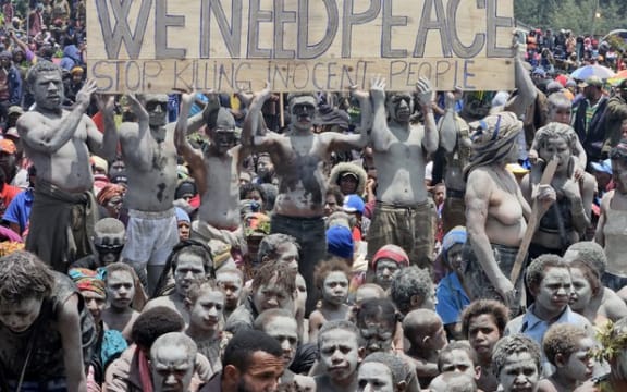 Local villagers hold a placard as they participate in a gathering near the Porgera Gold Mine in Enga province, Papua New Guinea on Sept. 23, 2024, almost one week after police reinforcements were rushed to the area in a bid to quell tribal violence that shuttered the key gold mine