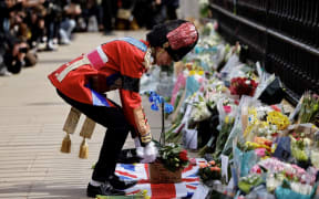 An ardent Royals fan lays a floral tribute at the front of Buckingham Palace in central London on April 9, 2021 after the announcement of the death of Britain's Prince Philip, Duke of Edinburgh.