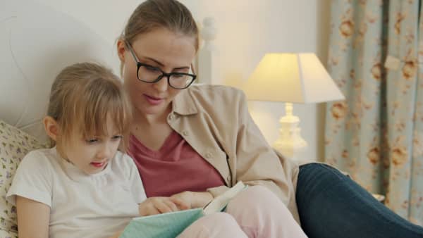 Mother reading to daughter in bed.