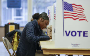 A woman casts her ballot during early voting for the US general election at a polling station at Ottawa Hills High School in Grand Rapids, Michigan, on November 3, 2024. (Photo by KAMIL KRZACZYNSKI / AFP)