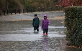 Children walk through the flood waters in Christchurch, NewÂ Zealand on May 30, 2021.Â MetService has put in place code red severe weather warning for the Canterbury region. (Photo by Sanka Vidanagama/NurPhoto via Getty Images)