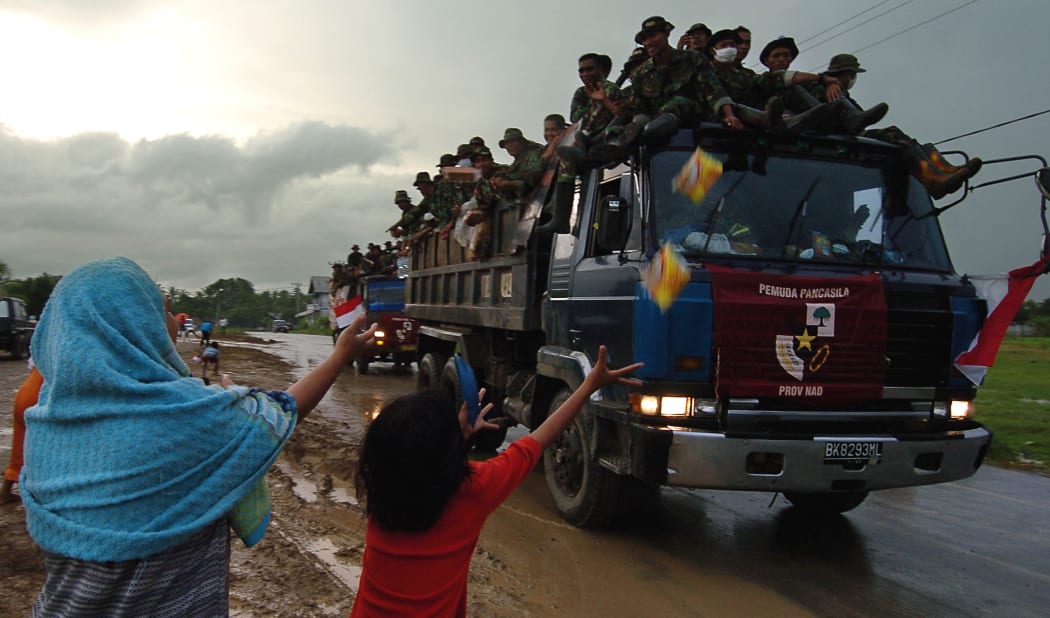 Indonesian refugees ask Indonesian soldiers for food as they pass by their refugee camp in Banda Aceh, 11 January 2005.