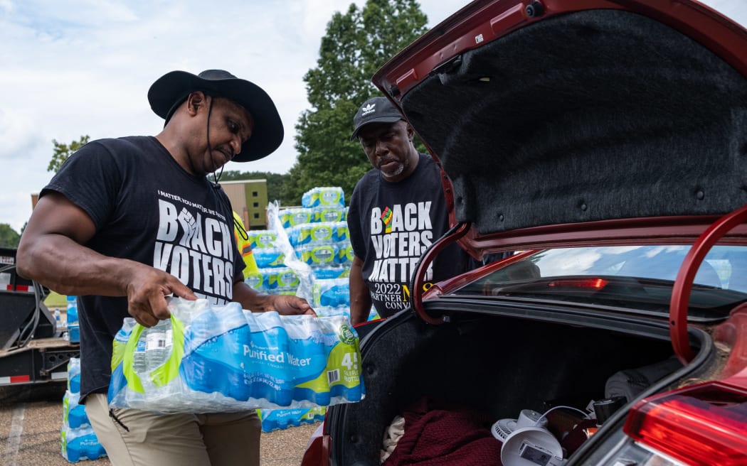 Residents distribute cases of water at Grove Park Community Center in Jackson, Mississippi, on September 3, 2022. - Jackson is enduring days without clean running water, with authorities urging those who still had supplies to shower with their mouths closed. The city, where 80 percent of the population is Black and poverty is rife, has been experiencing recurring water crises for years.  But this week's ordeal plunged Jackson into an emergency, with days of major flooding disrupting the operation of a critical but aging water treatment plant. (Photo by SETH HERALD / AFP)