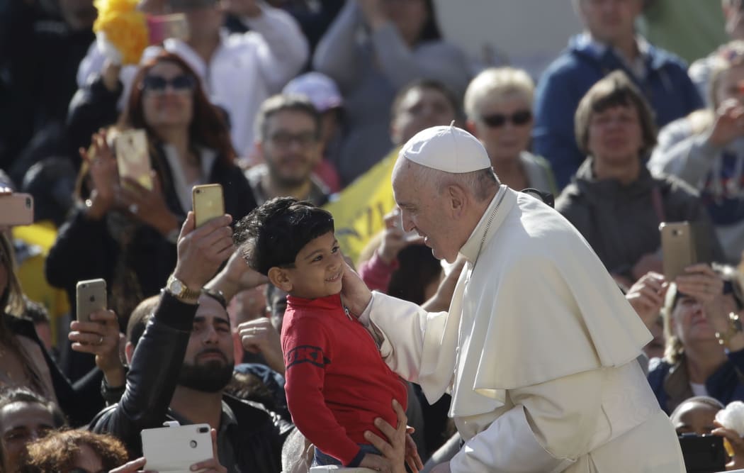 Pope Francis caresses a child as he arrives in St. Peter's Square at the Vatican for his weekly general audience, Wednesday, April 17, 2019.