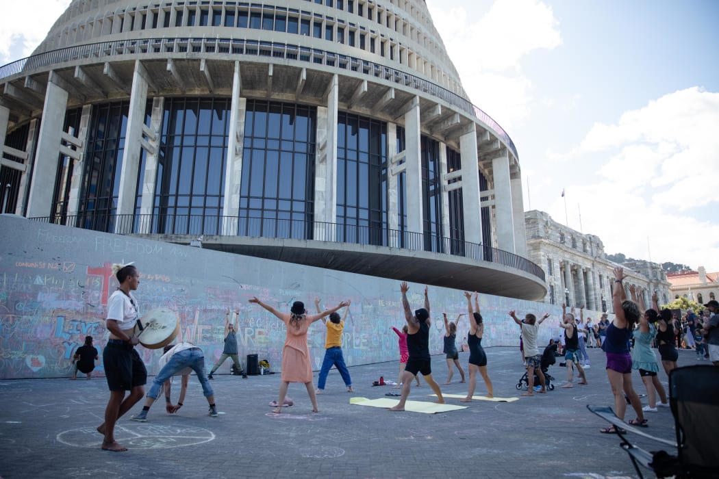 Anti-vaccine, anti-mandate protest in Wellington on Parliament grounds on 16 February 2022.
People doing yoga, stretching on the forecourt. Chalk art on the walls.