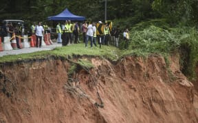 People inspect the damage after a landslide in Batang Kali, Selangor on December 16, 2022. - Nearly 20 people, including four children, were killed when a landslide struck a campsite at a Malaysian farm on Friday, officials said, with rescuers scouring the muddy terrain for those still missing. (Photo by Arif Kartono / AFP)