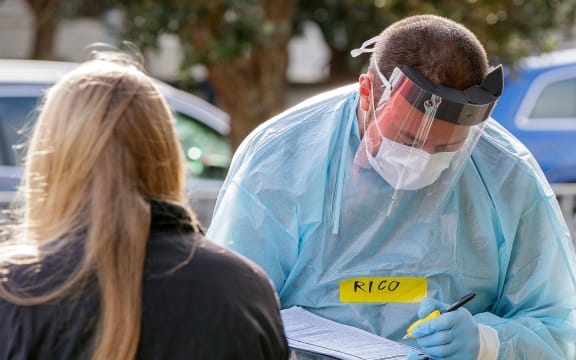 A health worker takes details at a COVID-19 testing station setup at Eden Park, National Sports Stadium, in Auckland on August 14, 2020.