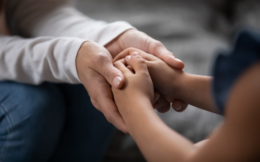 Holding hands of little kid girl, giving psychological help, supporting at home.