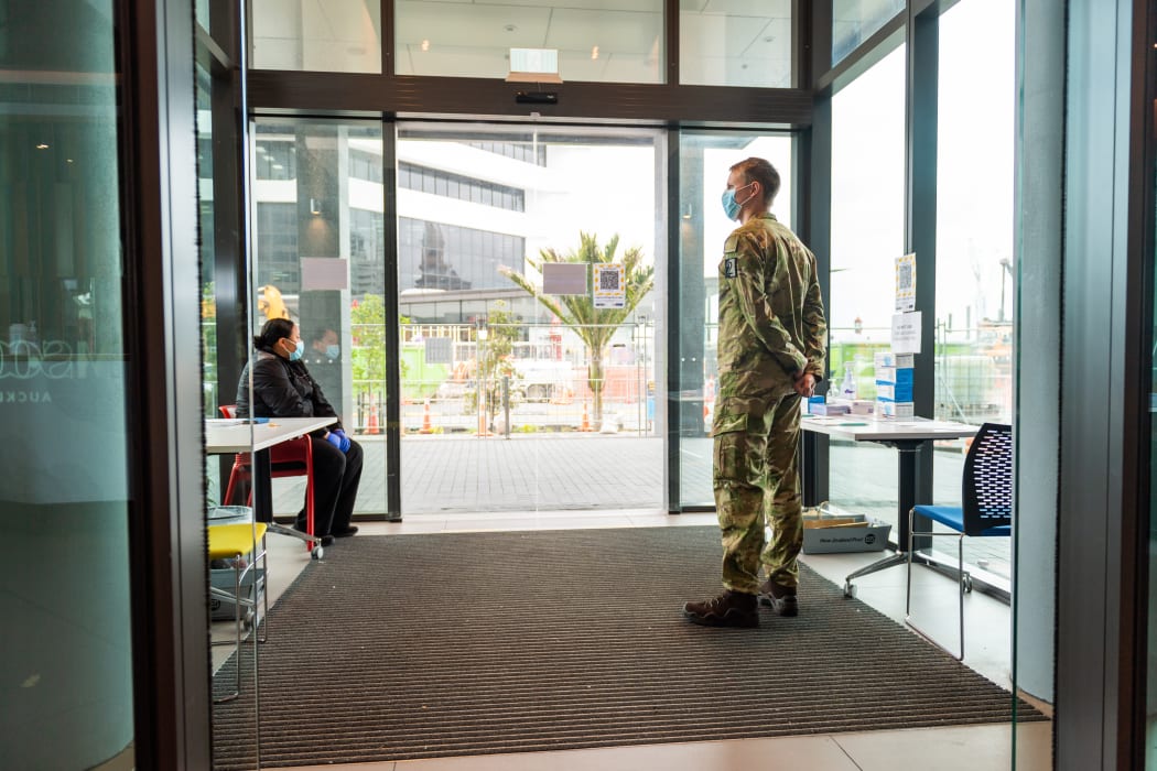 A security guard and soldier guarding an entrance to the M-Social Hotel, which is being used as a managed isolation facility, in Auckland.