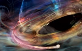 Swirls of color ranging from orange, yellow, and white to various shades of teal, surround a black oval representing a supermassive black hole.
