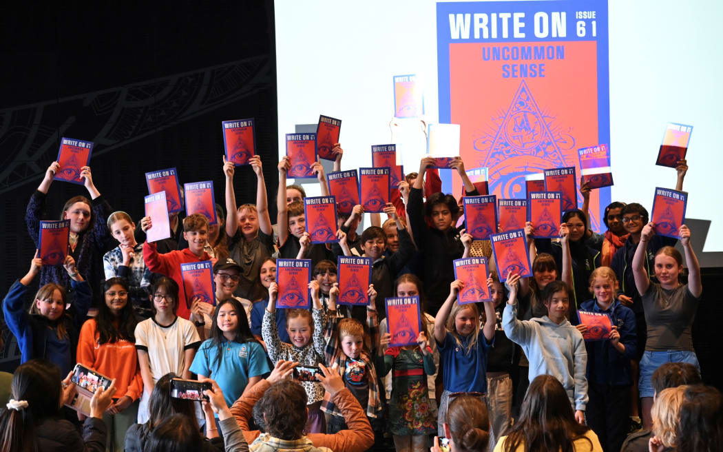 Child contributors hold up editions of a Write On magazine