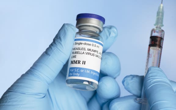 Nurse holding MMR (measles, mumps and rubella) vaccine vial in gloved hand with syringe. (Photo by SHERRY YATES YOUNG/SCIENCE PHOTO / SYO / Science Photo Library via AFP)