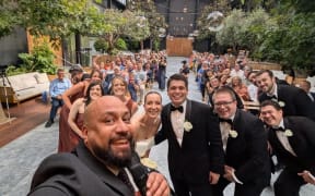 Auckland celebrant Nate Dunn takes a selfie with a couple and their guests from the stage.