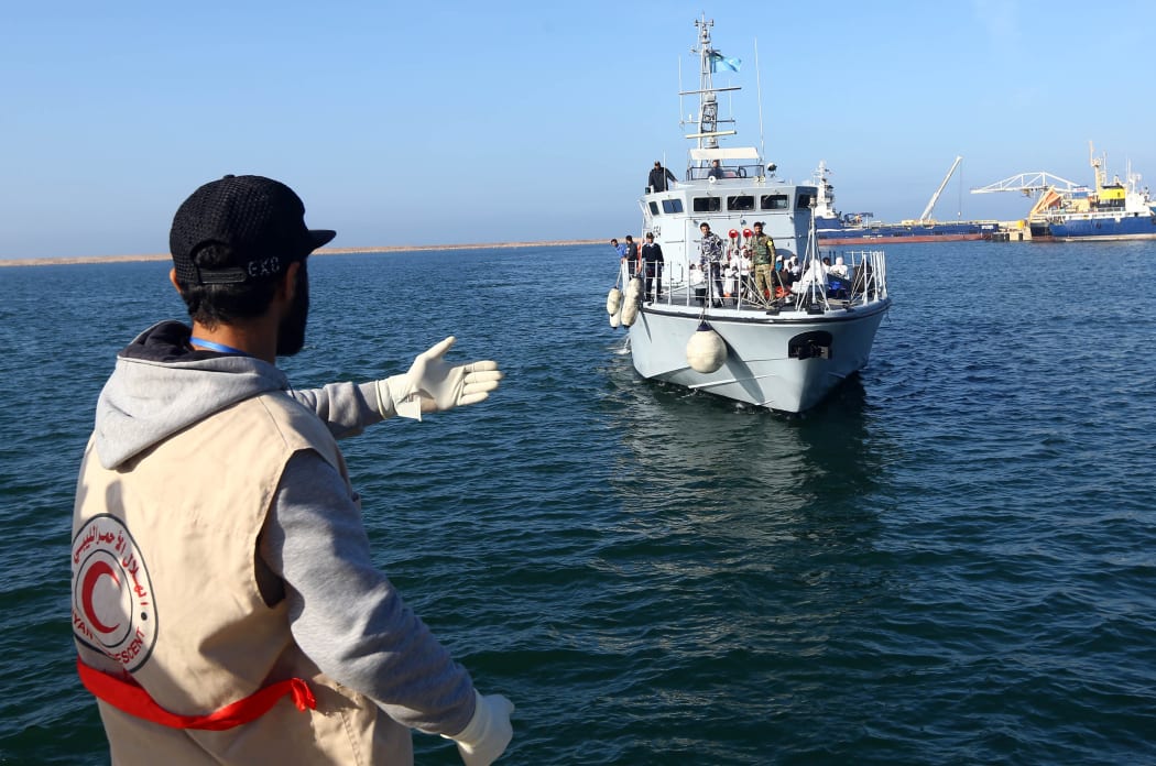 A Libyan Red Crescent worker awaits the arrival of a ship carrying African migrants at a naval base in Tripoli on 25 November 2017, after their rubber boat was rescued off the coast of Garabulli.