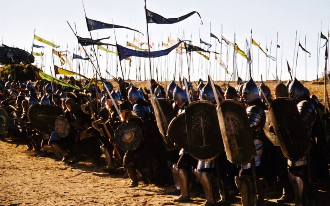 A still from Return of the King. The front lines of an army poised for battle, wearing shiny armour, carrying shields, and waving colourful banners.