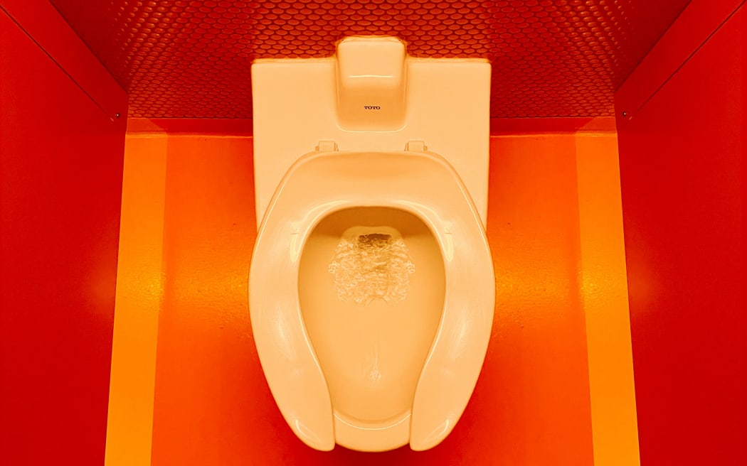 A toilet in a bright bathroom.