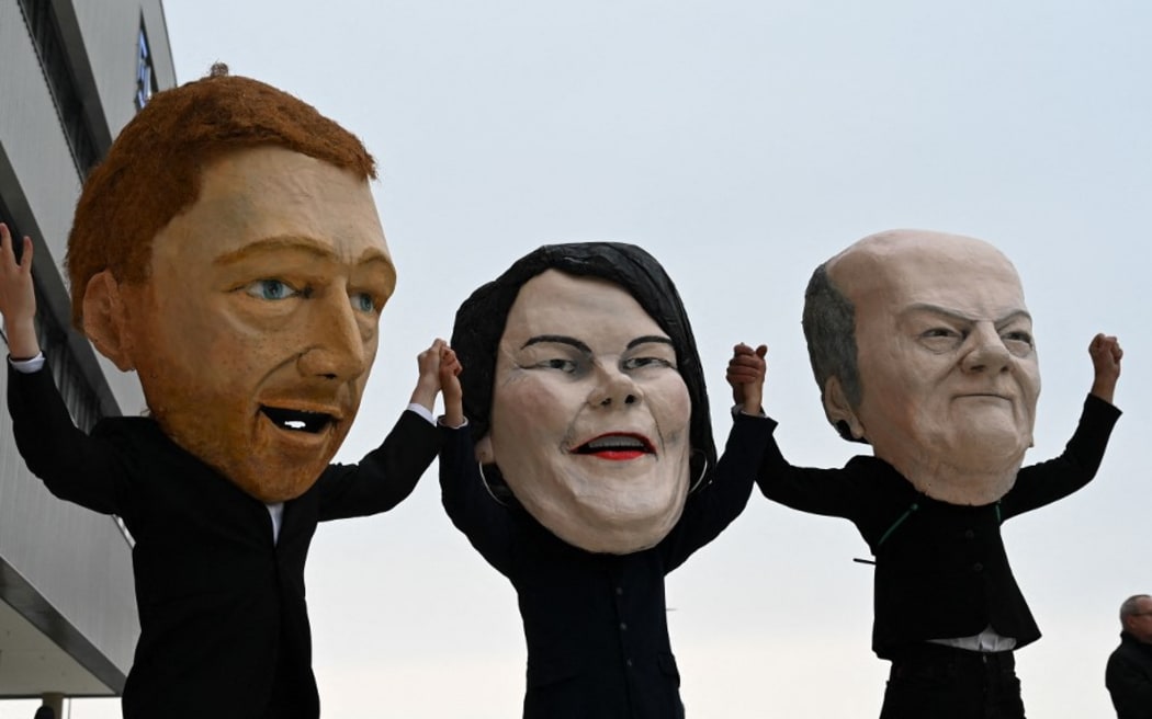 masks of (L-R) the leader of Germany's free democratic FDP party Christian Lindner, the co-leader of Germany's Greens (Die Gruenen) Annalena Baerbock and German Finance Minister, Vice-Chancellor and the Social Democratic SPD Party's candidate for chancellor Olaf Scholz