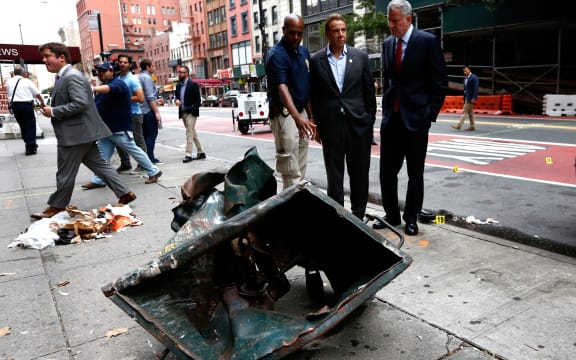 New York Mayor Bill de Blasio (centre) and New York Governor Andrew Cuomo (right) stand in front of a mangled dumpster while touring the site of the explosion in the Chelsea neighborhood of New York.