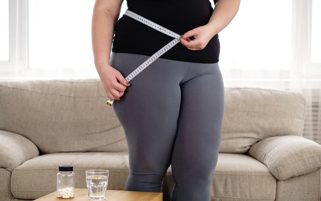 obese woman with pills and measure tape