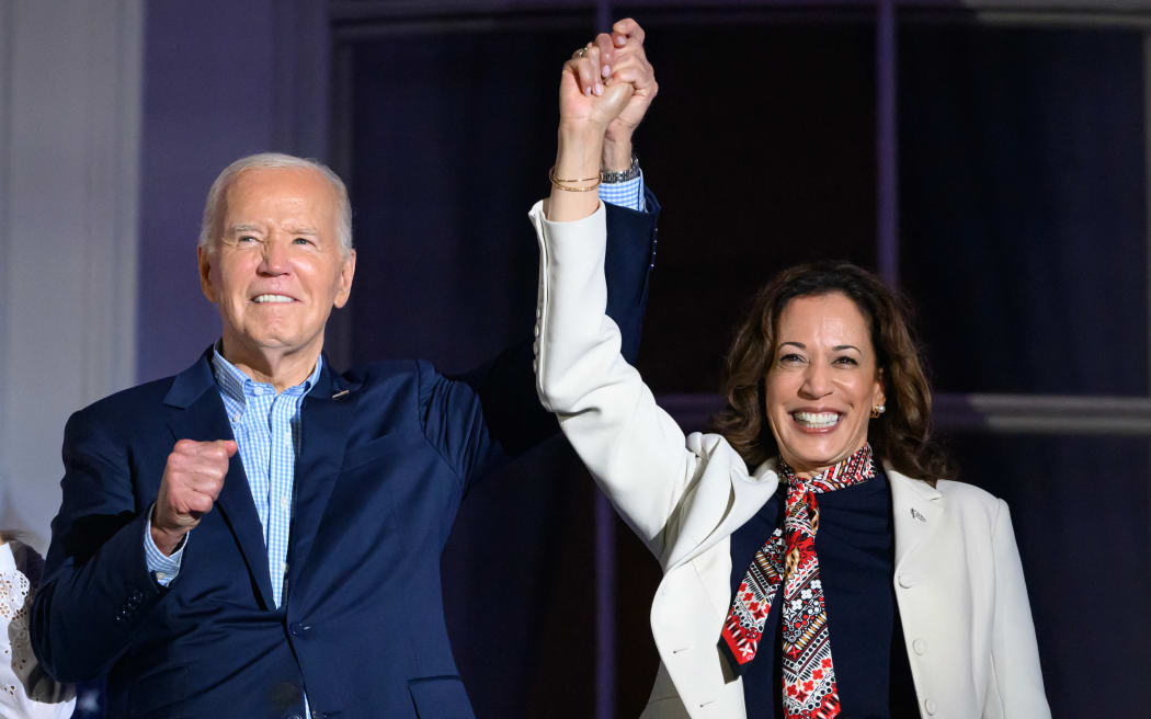 US President Joe Biden (L) and US Vice President Kamala Harris hold hands and gesture as they watch the Independence Day fireworks display from the Truman Balcony of the White House in Washington, DC, on July 4, 2024.