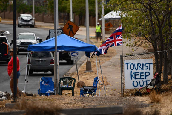 The Flag of Hawaii waves by a sign reading "Tourist Keep Out" in the aftermath of the Maui wildfires in Lahaina, Hawaii.