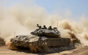 This picture taken from Israel's southern border with the Gaza Strip shows an Israeli tank rolling along the border with the Palestinian territory on April 16, 2024, amid the ongoing conflict between Israel and the militant group Hamas. (Photo by Menahem KAHANA / AFP)