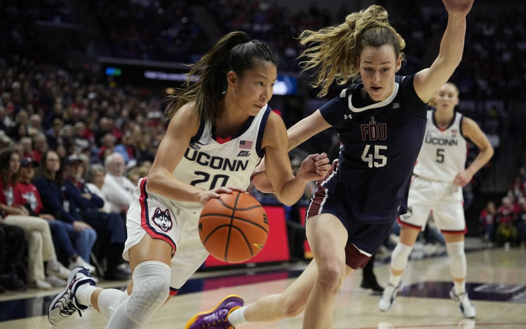 Kaitlyn Chen #20 of the Connecticut Huskies drives to the rim against Lilly Parke #45 of Fairleigh Dickinson Knights during the first half of an NCAA women's basketball game