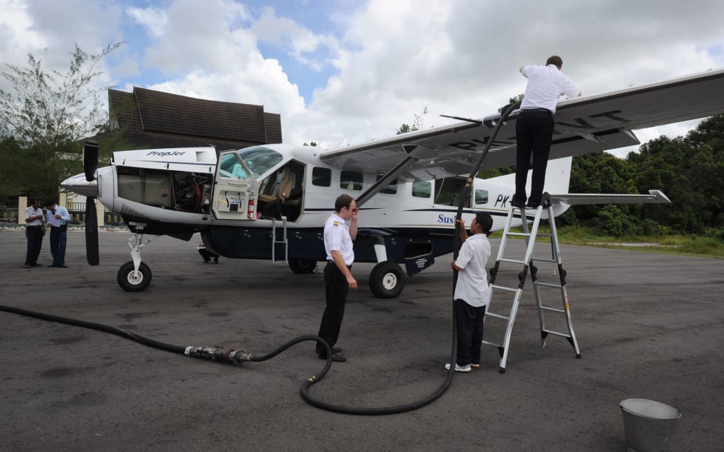 n this photograph taken on July 5, 2011 two Susi Air pilots (R and 2nd R) refuel a Cessna Grand Caravan aircraft in Pangkalanbun, Central Kalimantan province.