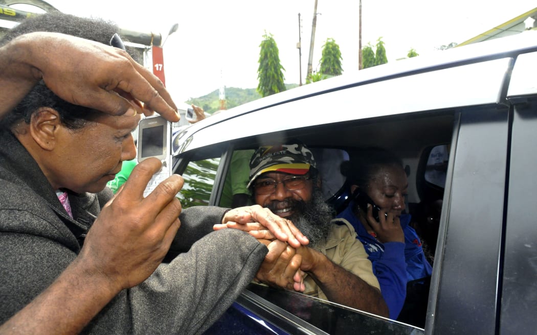 Papuan pro-independence activist Filep Karma (inside vehicle) shakes hands with his supporters after being released from prison in Abepura, Papua province, on November 19, 2015.